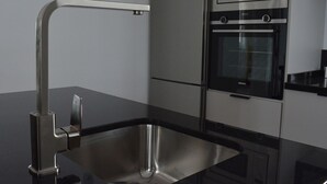 Et moderne køkken med en stålvask, indbygget ovn og mikroovn.