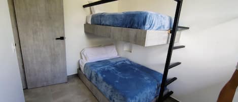 A bunk bed with a blue mattress and a white pillow.