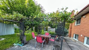 A patio with a table and chairs, a pergola, and a brick building in the background. - Short Walk to the Falls,SuperLargeApt,Free parking (Niagara Falls)