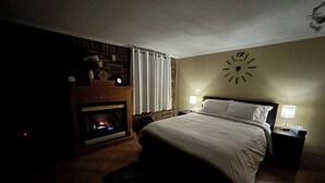 A bedroom with a bed, a fireplace, a clock on the wall, and two bedside lamps. - Short Walk to the Falls,SuperLargeApt,Free parking (Niagara Falls)