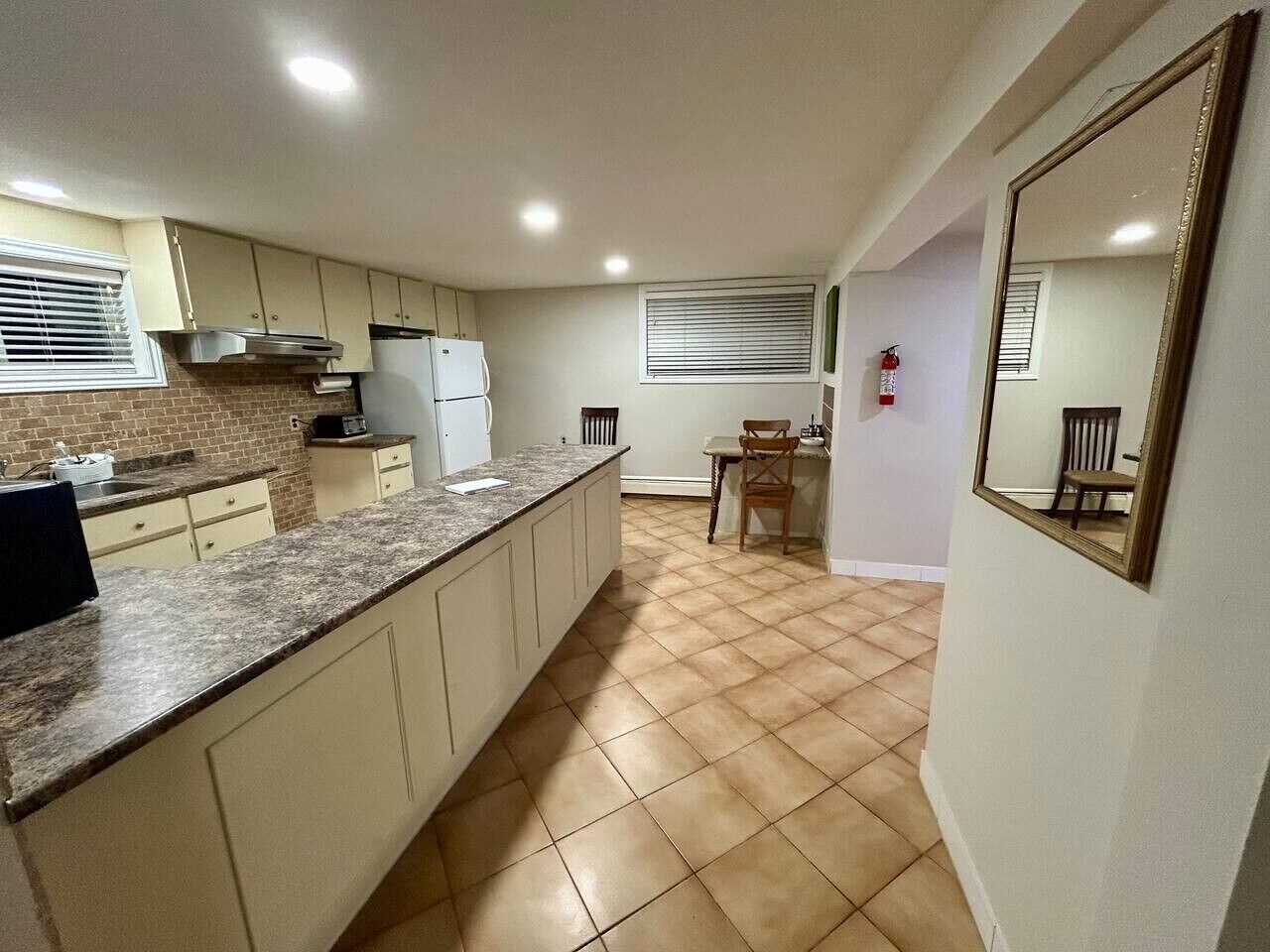 Una cocina con encimera de granito, armarios blancos, estufa y refrigerador.