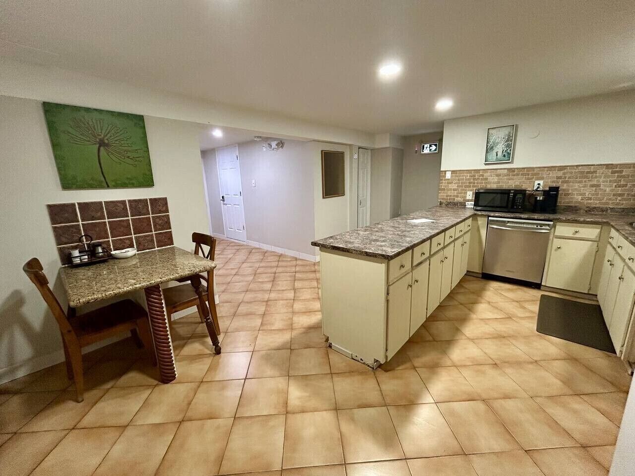 Una cocina con una mesa de comedor, sillas, microondas y lavavajillas.