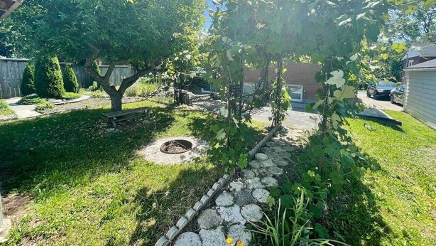 A backyard with a tree, a fire pit, and a stone pathway. - Short Walk to the Falls,SuperLargeApt,Free parking (Niagara Falls)