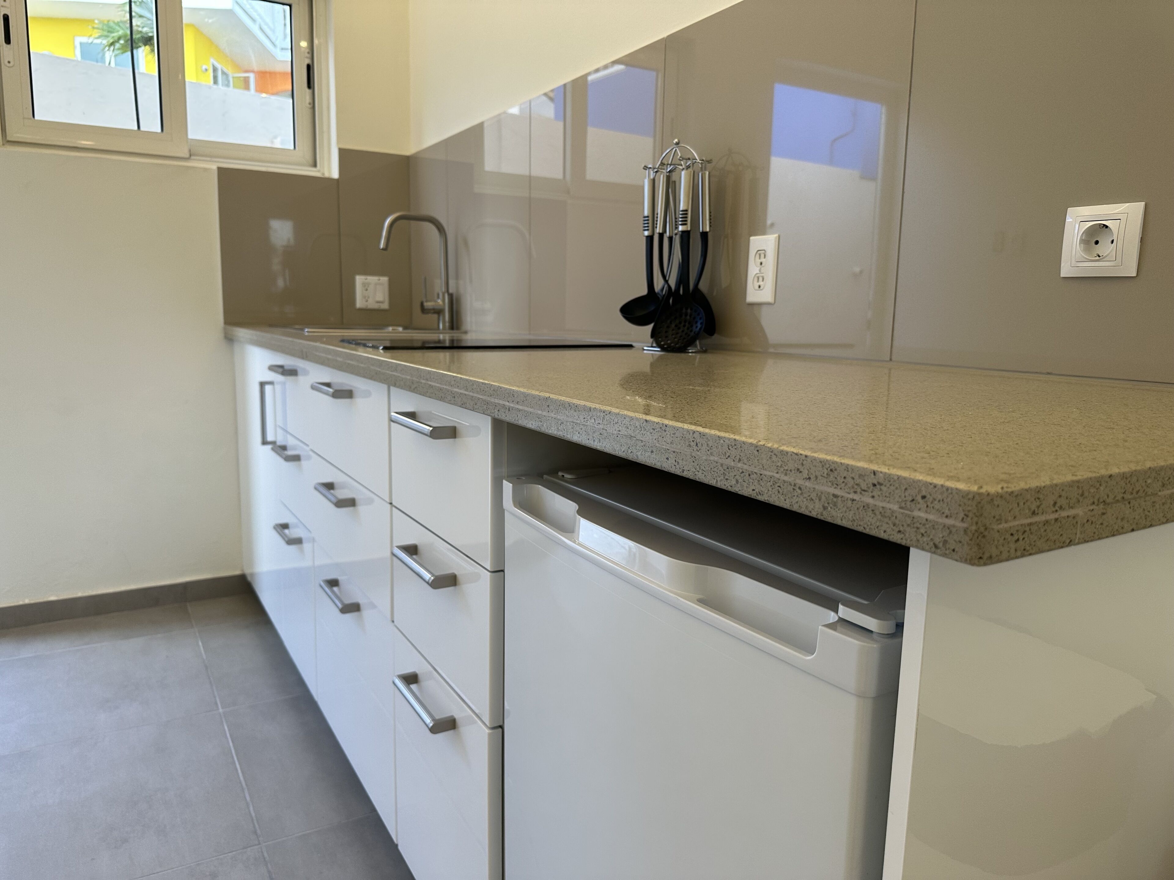 A kitchen with white cabinets, a granite countertop, a stainless steel sink, and a dishwasher.
