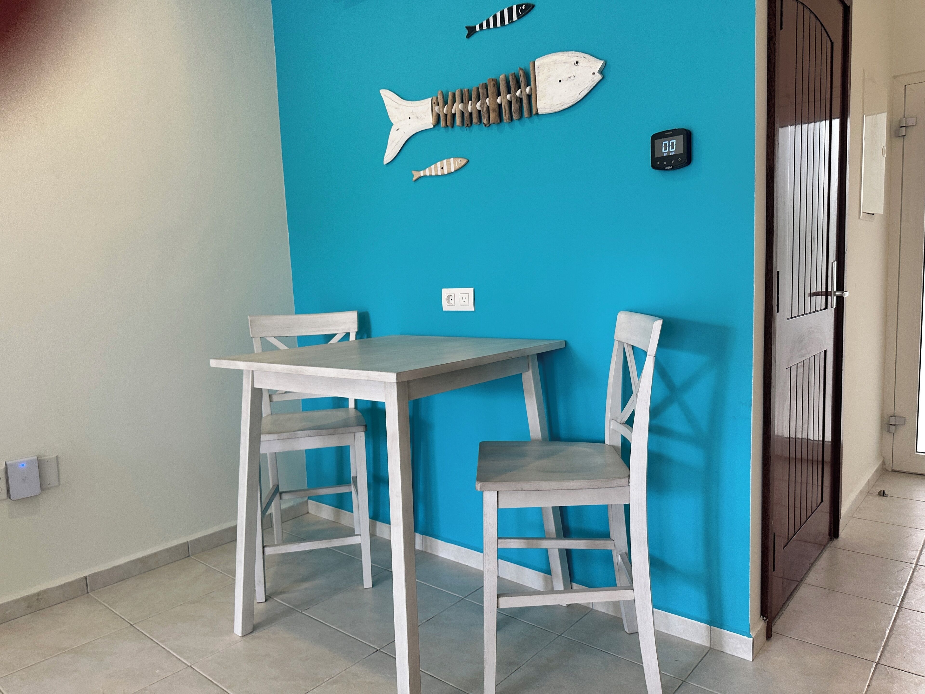 A room with a blue wall, a white table, and two white chairs.