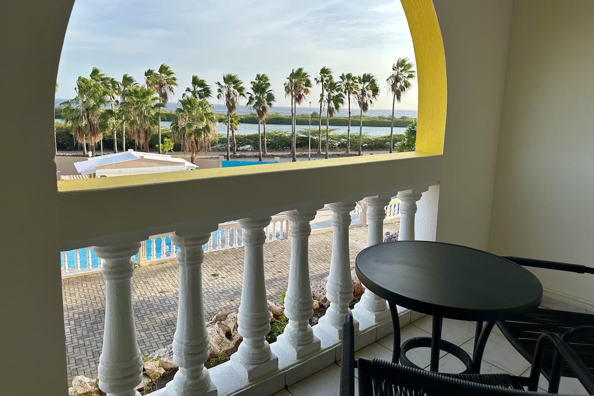 A balcony with a view of palm trees and a pool.