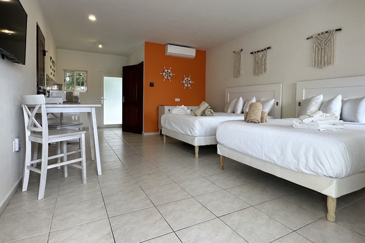 A hotel room with two beds, a dining table, and chairs.