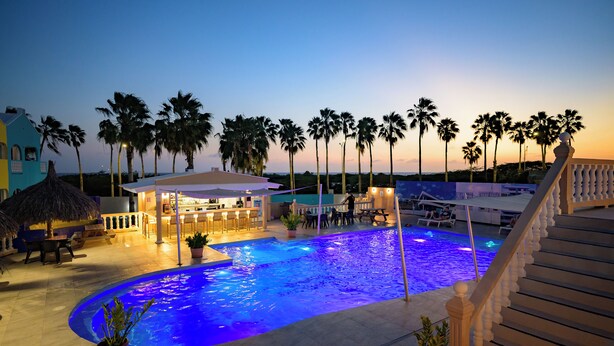 A swimming pool with a bar area, palm trees, and a staircase. - MERAKII SEAVIEW ESCAPE CURACAO (Willemstad)