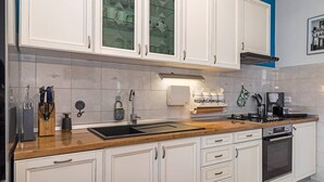 A modern kitchen with white cabinets, a wooden countertop, and a built-in oven. - Holiday Home Endi - rural escape with pool (Danilo Kraljice)