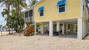 A two-story yellow building with a covered porch, wooden staircase, and a view of the beach. - New! Oceanview Oasis whole house - Theater - Screened Porch - Sundeck - Grill (Marathon)