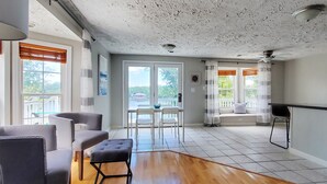 A spacious living area with a wooden floor, a dining table with chairs, and a seating area with a bench.