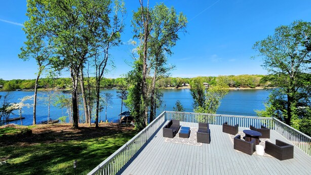 A deck with outdoor furniture overlooking a lake.