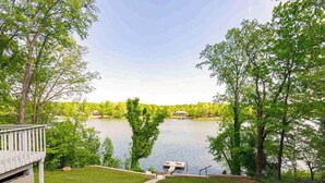 A lakeside property with a deck, a dock, and a grassy lawn.
