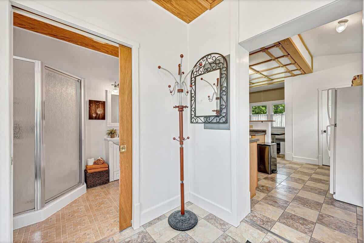 Un couloir avec un porte-manteau, un miroir et une porte donnant sur une salle de bain.