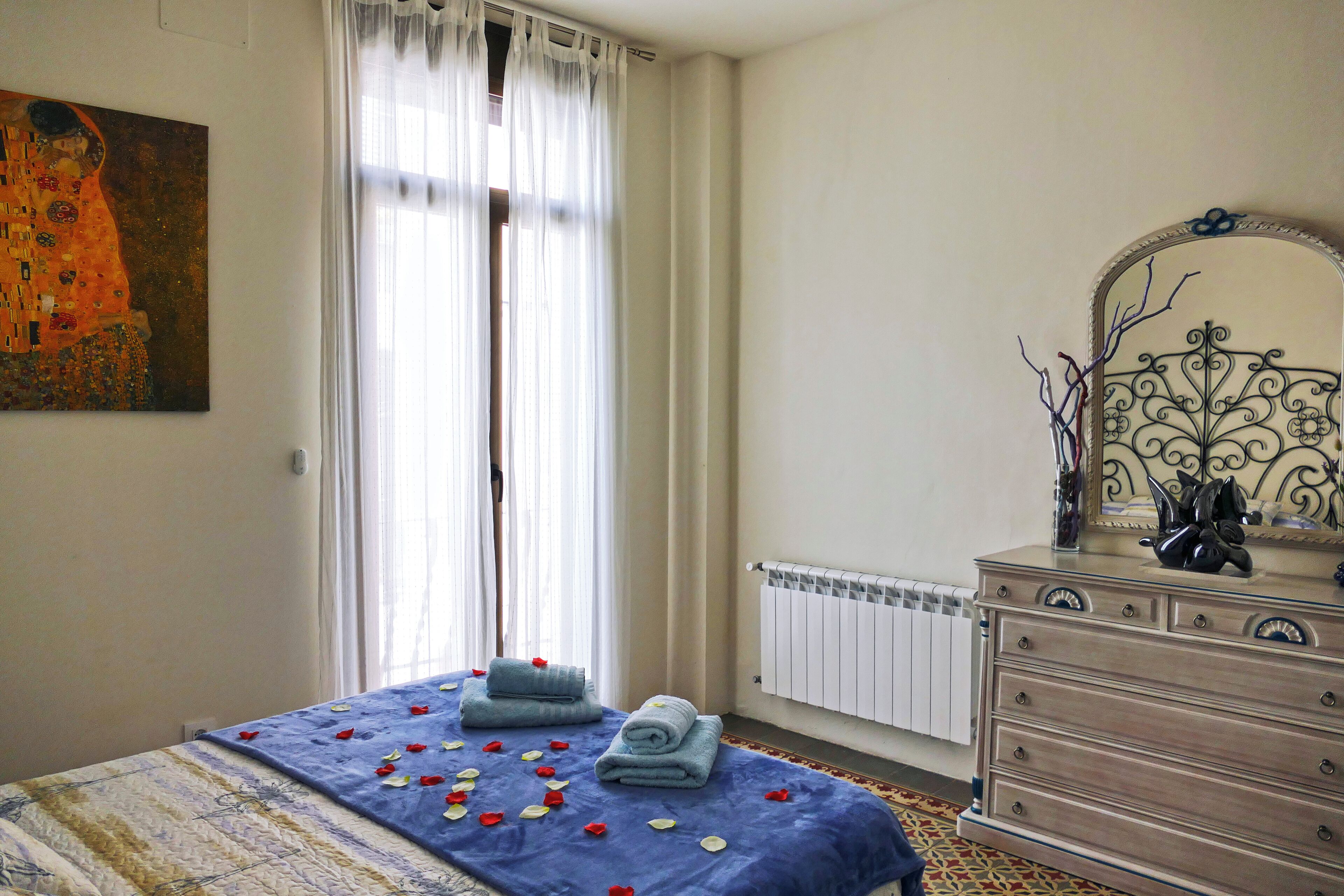 Un dormitorio con cama, cómoda, radiador y un cuadro en la pared.