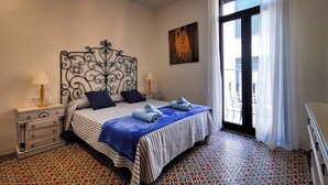 Une chambre bien rangée, avec un lit, des tables de chevet, un ventilateur de plafond et une grande fenêtre avec des rideaux.