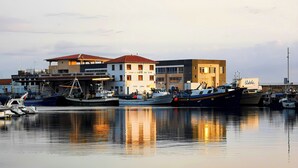 Un port de plaisance où sont amarrés plusieurs bateaux, un restaurant et des bâtiments arborant des enseignes commerciales.