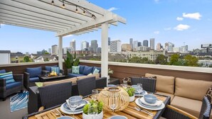 Un patio en la azotea con mobiliario exterior, una chimenea y vistas a la ciudad.