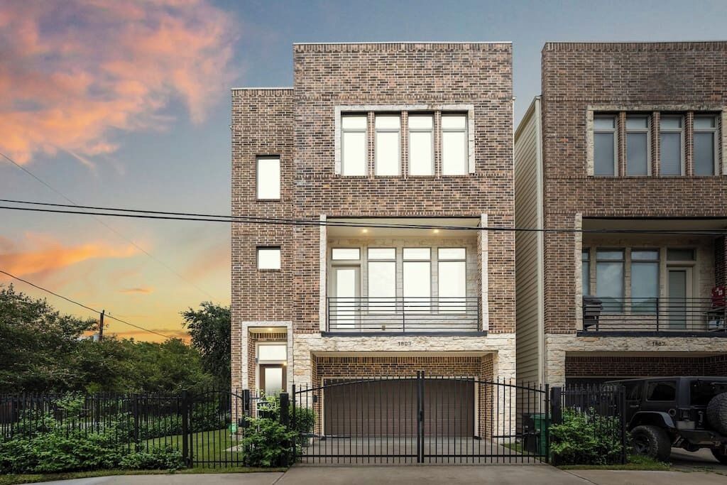 A modern two-story building with a brick facade, large windows, and a gated entrance.
