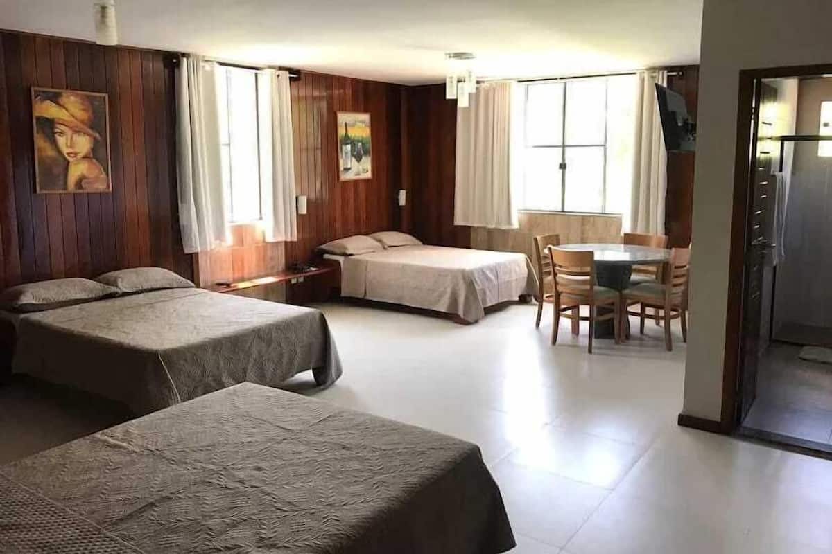 Une chambre d’hôtel avec deux lits simples, une table à manger avec des chaises et un coin cuisine.