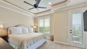 Une chambre à coucher avec un lit, un ventilateur de plafond, deux fenêtres équipées de stores, une porte donnant sur une vue agréable et un petit panier.