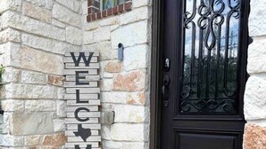 Una casa de piedra con una puerta negra y un letrero que dice 'WELCOME'.
