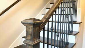 Una escalera con escalones de madera oscura y barandillas de metal negro.