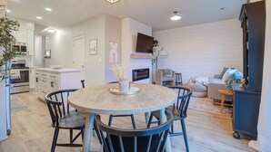 Een moderne keuken met witte kastjes, een eettafel met stoelen en een ingebouwde oven.