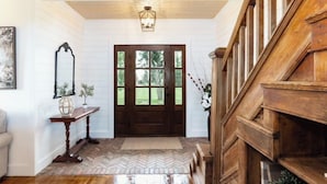 A wooden staircase leading to a dark wooden door with a window.