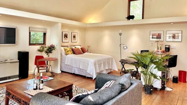 A bedroom with a bed, a desk, a chair, and a television.