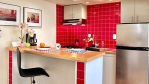 A modern kitchen with red tiles, stainless steel appliances, and a wooden island with seating.