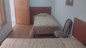 A room with two beds, a wooden door, a small wall-mounted picture, and a patterned floor. - C. Deán Valdivia 120 (Arequipa)