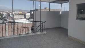 A balcony with a metal railing, a tiled floor, and a view of a cityscape with buildings and mountains in the distance. - C. Deán Valdivia 120 (Arequipa)