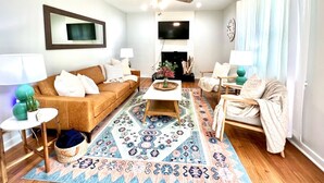 Un salon avec un canapé marron, une table basse, un tapis à motifs, un ventilateur de plafond et un téléviseur.