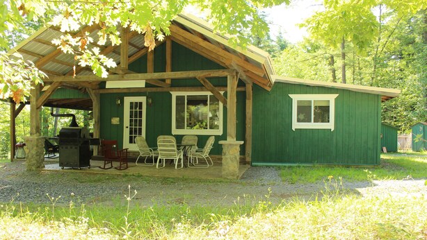A rustic cabin with a porch, outdoor seating, and a grill area. - SUGAR MAPLE CHALET (Dansville)