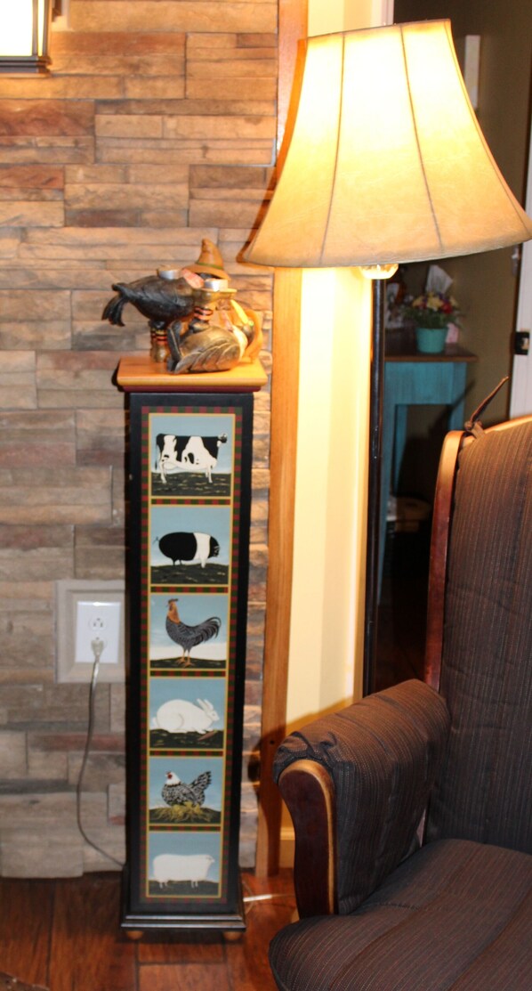A lamp with a decorative base, a chair, and a wall with a power outlet. - SUGAR MAPLE CHALET (Dansville)