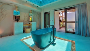 Un baño moderno con una bañera independiente, un tragaluz y un amplio ventanal corredera que da a un espacio exterior.