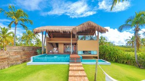Una casa moderna con piscina, techo de paja y una hamaca.