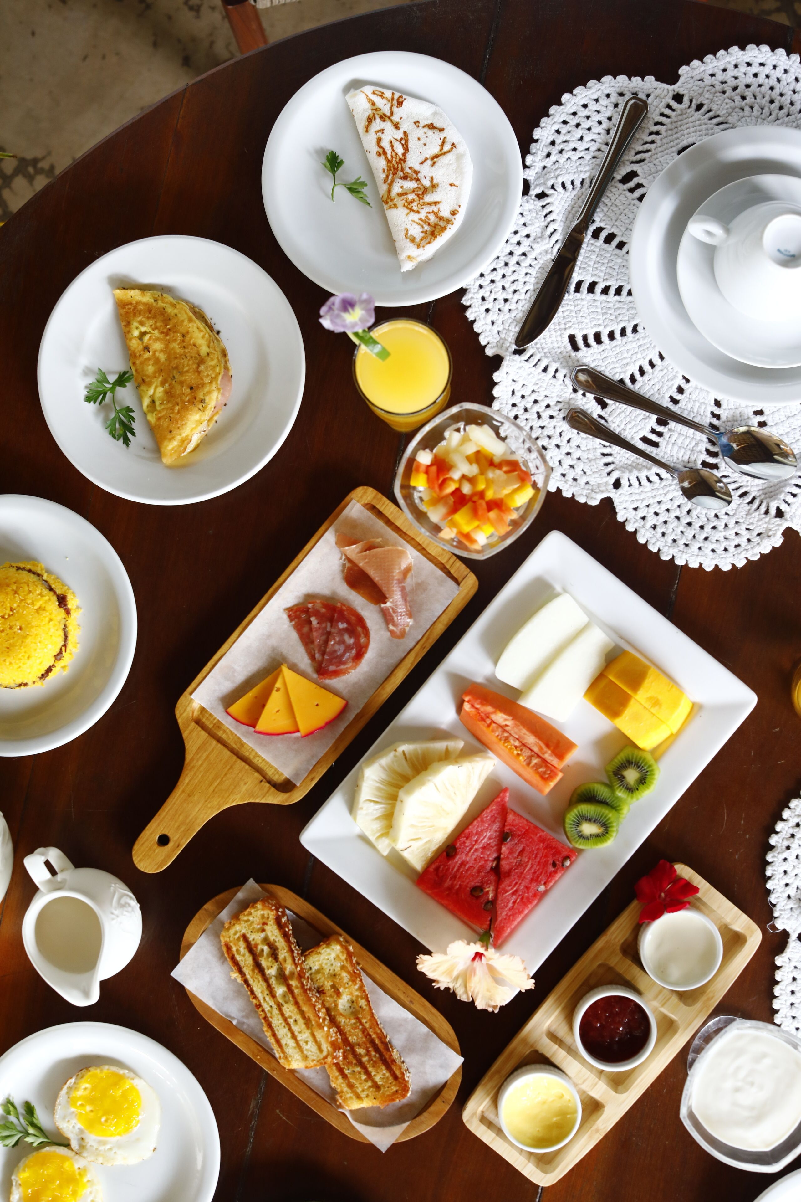 A breakfast setting with various dishes including eggs, toast, cheese, and fruits.