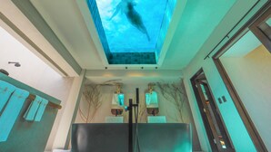 Un baño moderno con tragaluz, dos lavamanos y un espejo grande.