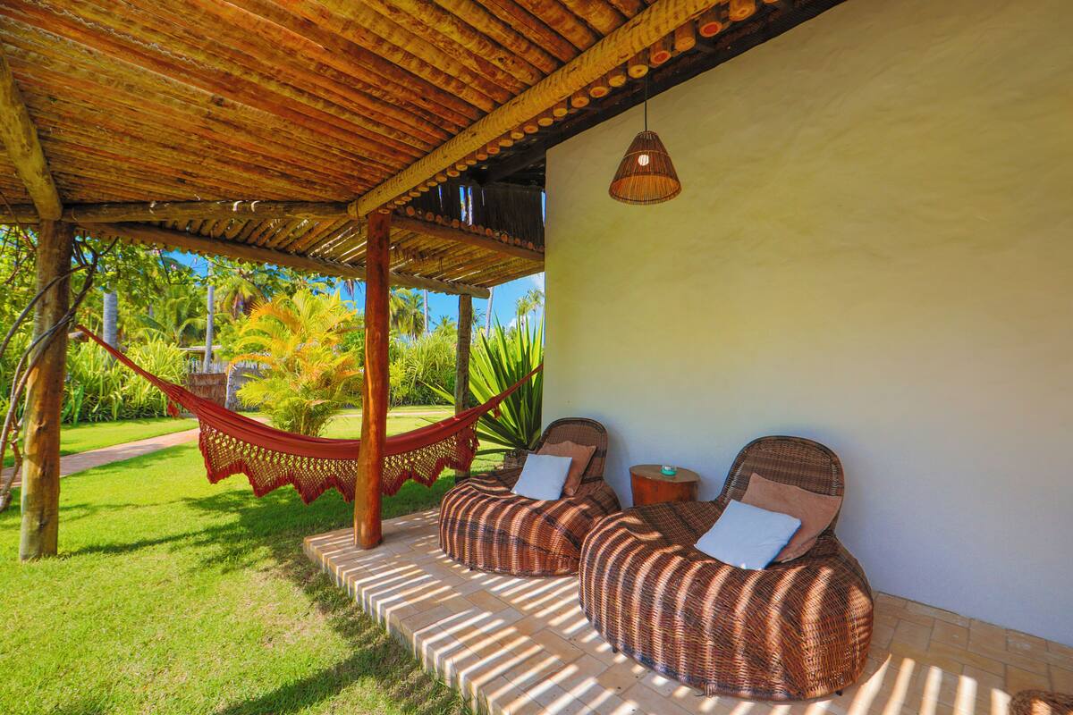 A covered outdoor seating area with wicker furniture and a hammock.