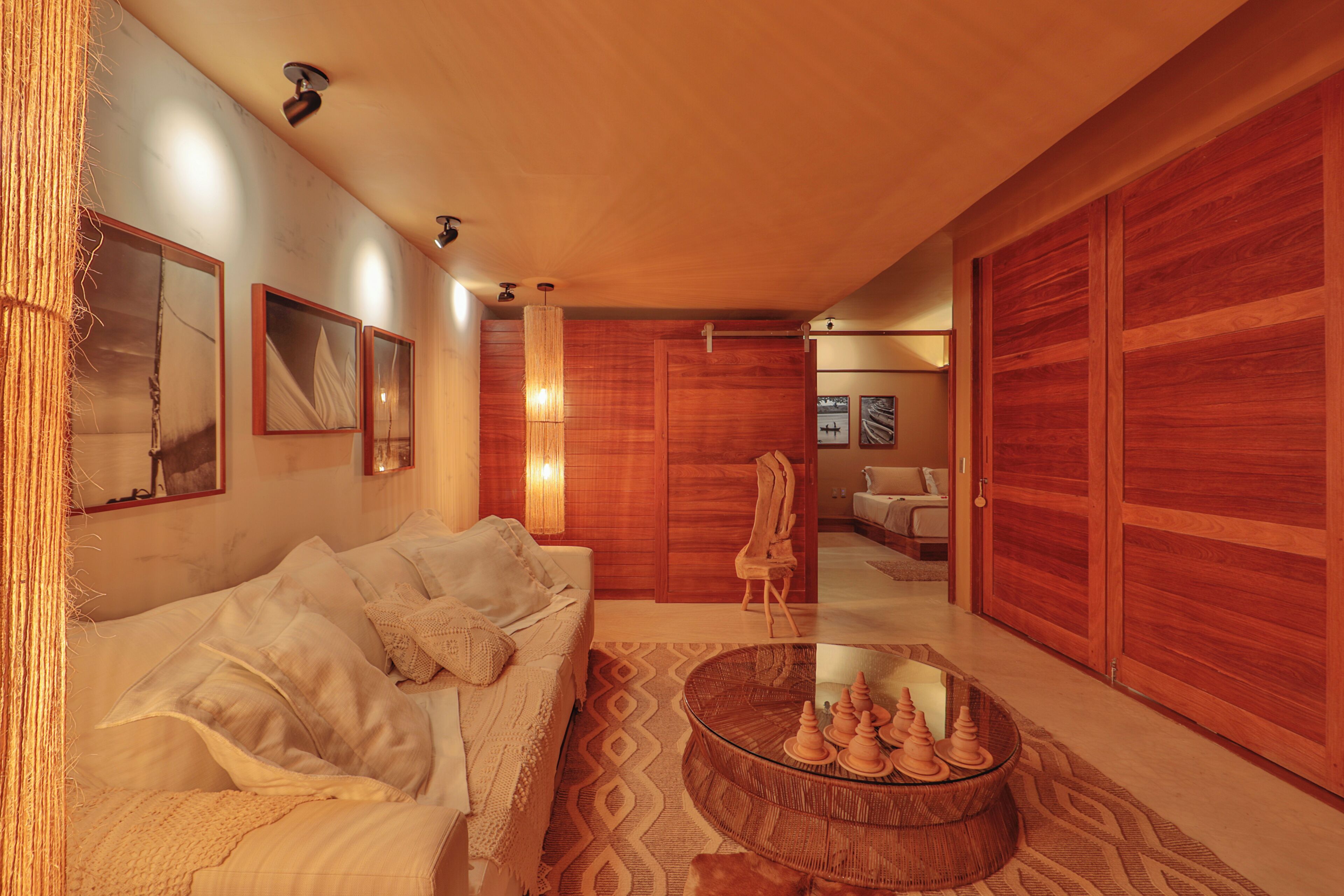 A modern living room with a sofa, a glass coffee table with decorative items, and wooden sliding doors.