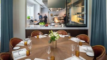 A dining area with a round table set for six, surrounded by chairs.