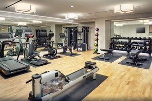 Un gimnasio con diversos equipos de ejercicio, incluyendo cintas de correr, bicicletas estáticas y pesas libres.