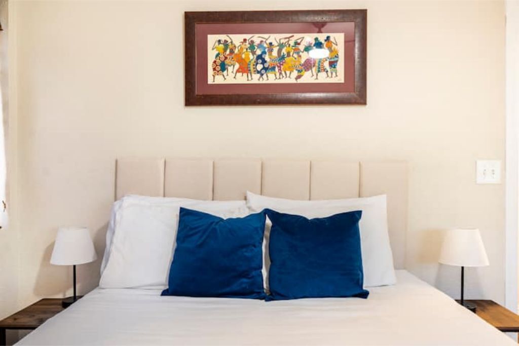 Ein Hotelzimmer mit einem Bett, zwei Nachttischen und einem gerahmten Kunstwerk an der Wand.