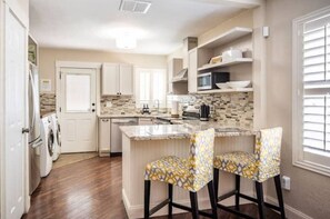 Kitchen area with central island, sink, microwave, and bar stools.