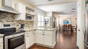 Una cocina moderna con armarios blancos, microondas integrado y una isla grande con pileta.
