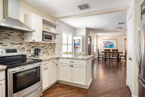 Enjoy cooking in this well-equipped kitchen with a black stove, microwave, and coffee maker.