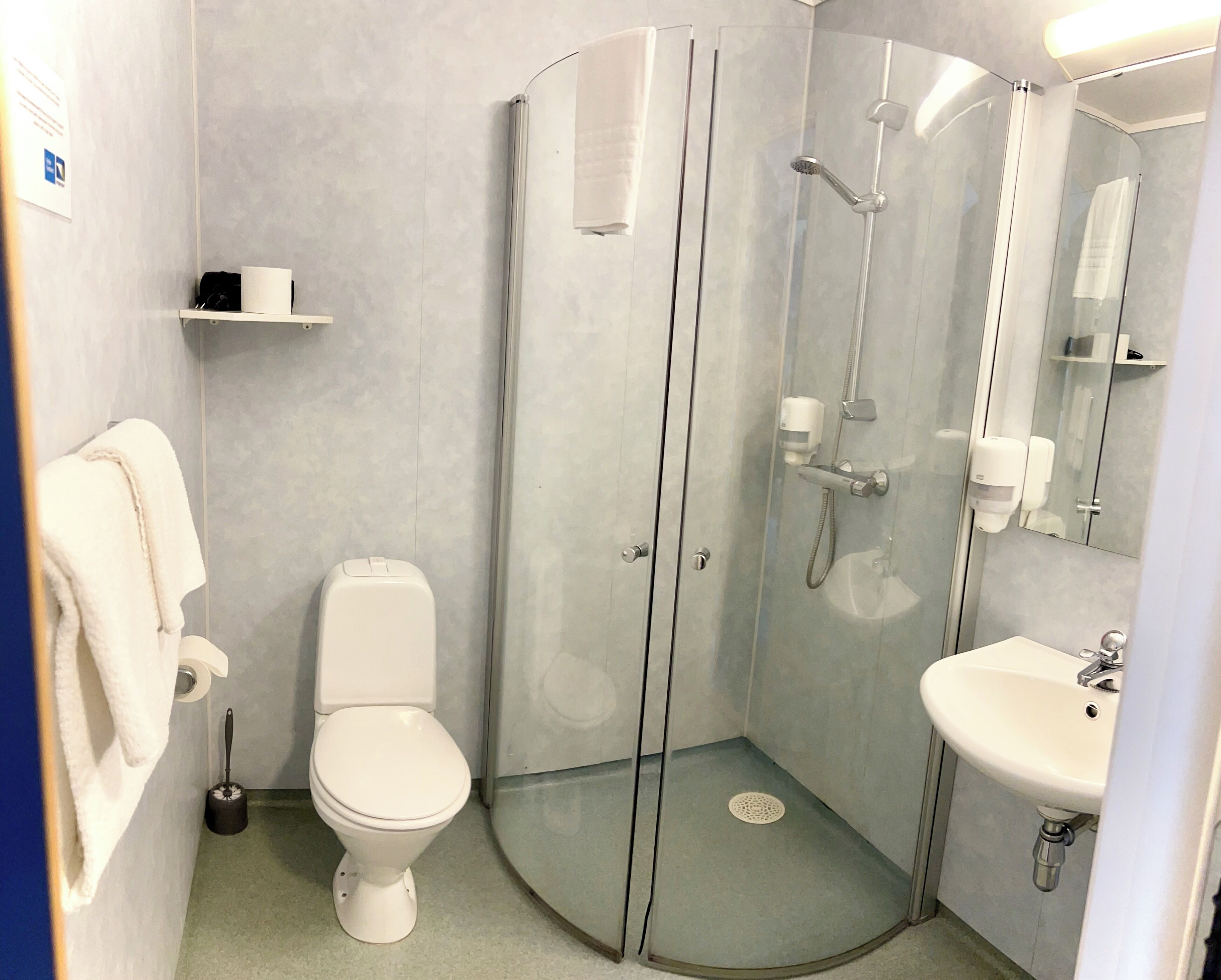 A modern bathroom with a toilet, a glass-enclosed shower, and a sink.