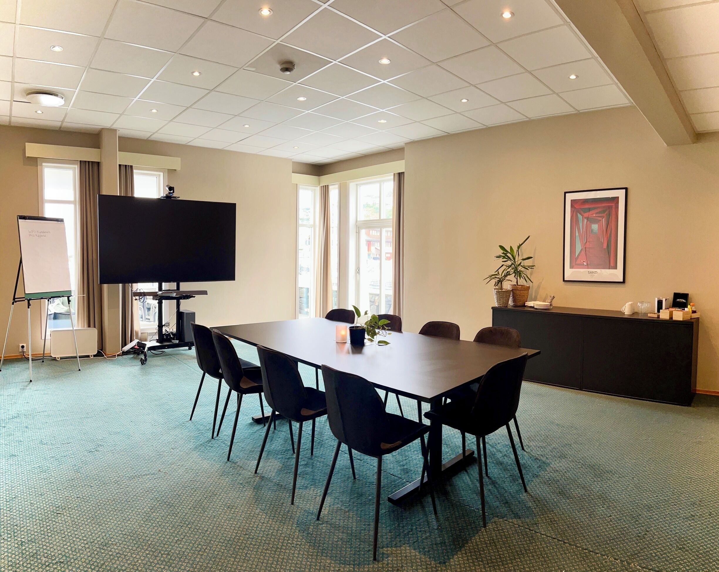 A conference room with a large table, chairs, a whiteboard, a TV, and a potted plant.